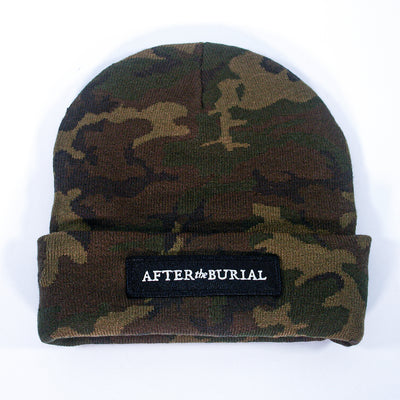 A camouflage-patterned After The Burial beanie with an adjustable cuffed brim. Features a black rectangular patch with white "AFTER the BURIAL" text on front. One size fits all. Displayed on a plain white background.